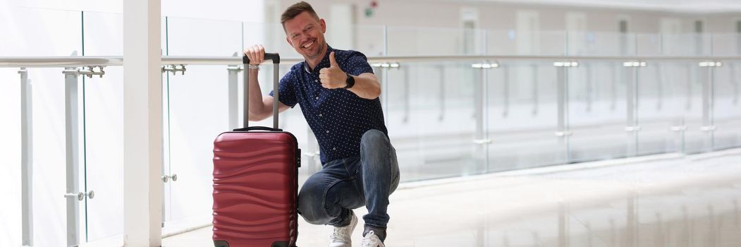 Man with suitcases showing ok gesture in hotel corridor. Quality rest in hotel concept