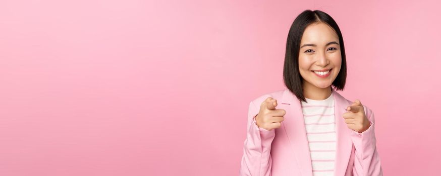 Its you, congrats. Smiling enthusiastic korean corporate lady, businesswoman pointing fingers at camera congratulating, praising you, standing over pink background.