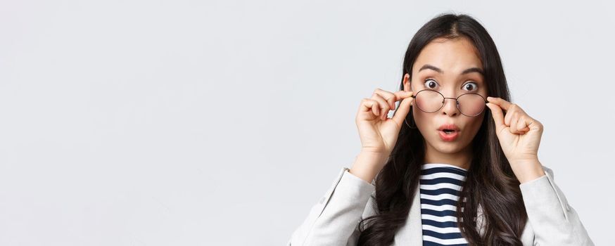 Business, finance and employment, female successful entrepreneurs concept. Close-up of surprised and impressed asian office worker take-off glass and widen eyes astonished, see awesome promo deal.