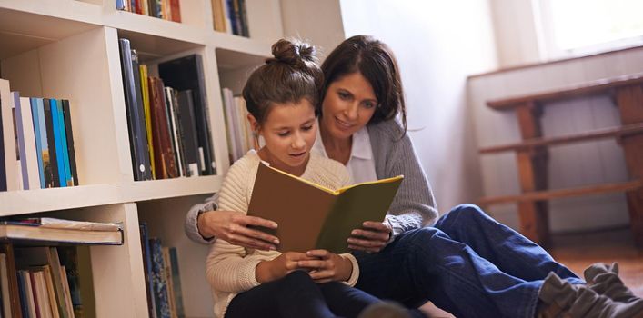 A mother and daughter reading a book together at home.
