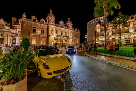 Monaco, Monte Carlo, 21 August 2019: Luxury sport car near the hotel Paris and casino in night, lights of the place Casino, a lot of tourists. High quality photo