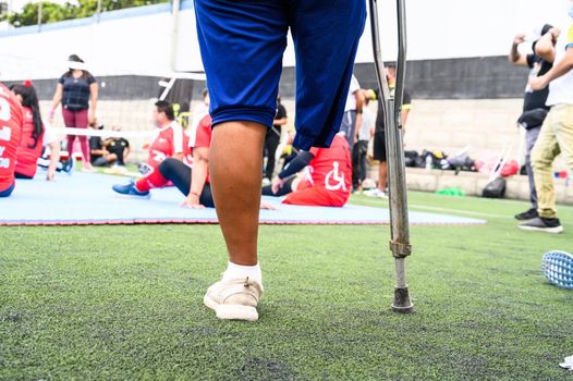 Disabled man with one leg on crutches watching a match