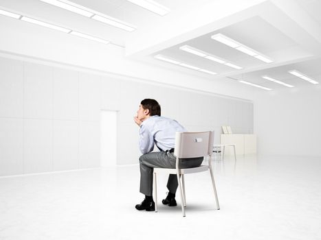 young businessman sits on an office chair, thoughtful and looking up