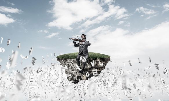 Young man wearing suit and glasses sitting on island and playing violin