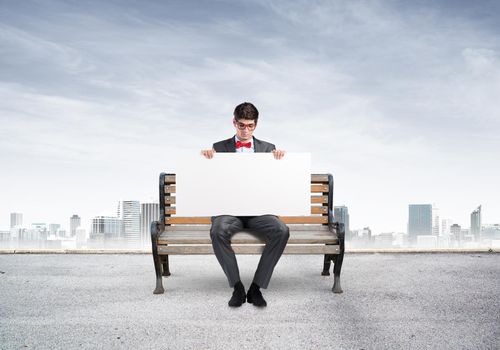 Young businessman holds a large white banner. sits on the bench