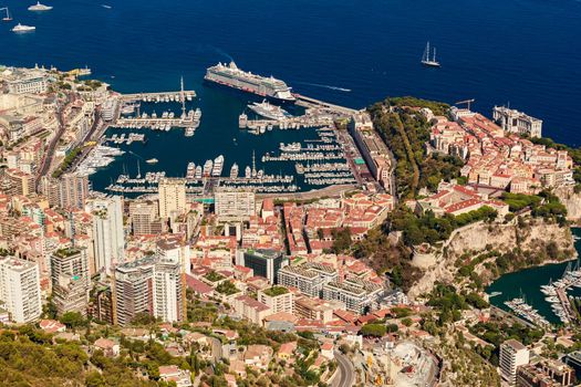 Aerial view of port Hercules of Monaco at sunset, Monte-Carlo, huge cruise ship is moored in marina, view of city life from La Turbie mountain, a lot of mega yachts and boats. High quality photo