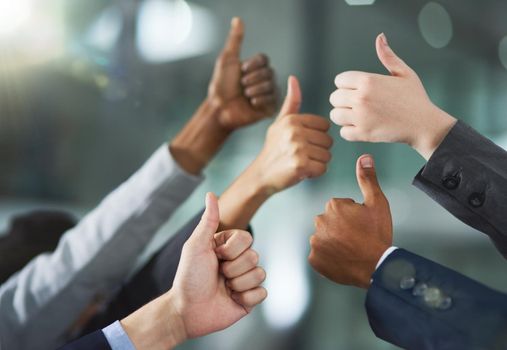 Shot of a group of office workers giving thumbs up together.