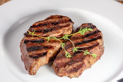 Grilled marbled beef steak lies on a white plate