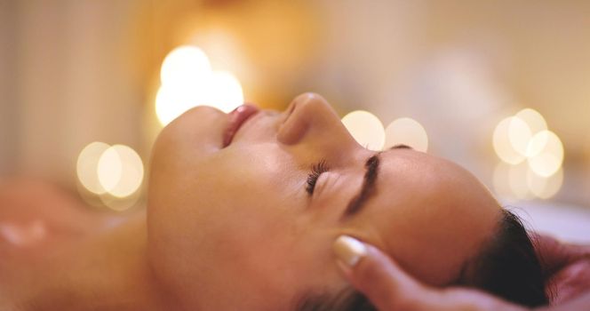 Closeup shot of a beautiful young woman enjoying a head massage at a beauty spa.
