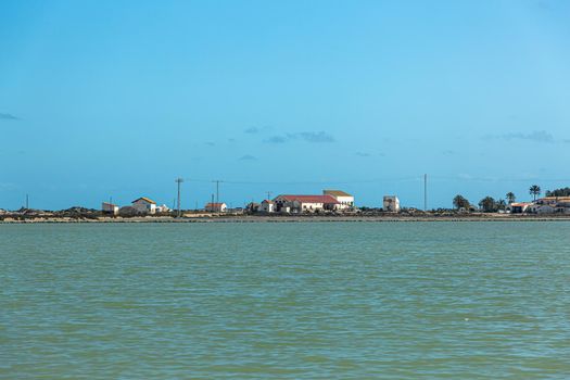 Some buildings on the shore of a salt lake. Blue sky and green water.