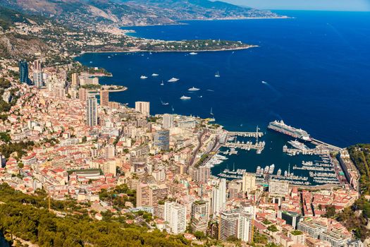 Aerial view of port Hercules of Monaco at sunset, Monte-Carlo, huge cruise ship is moored in marina, view of city life from La Turbie mountain, a lot of mega yachts and boats. High quality photo