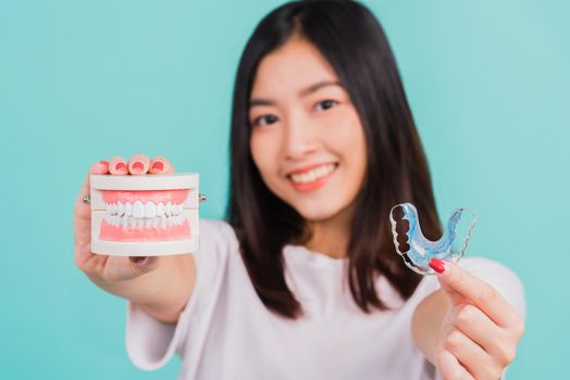 Portrait young Asian beautiful woman smiling holding silicone orthodontic retainers for teeth retaining tools after removable braces, Female hold model teeth before, Orthodontics dental healthy care