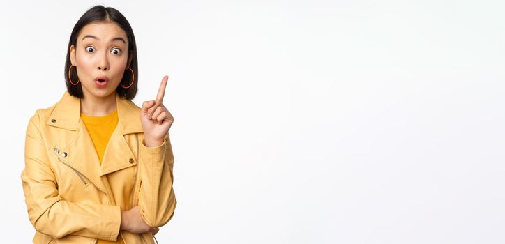 Idea. Enthusiastic asian girl has suggestion, raising finger up, eureka gesture, got excellent plan or solution, standing over white background.