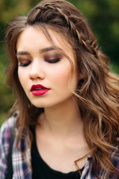 Portrait of incognito woman with volumed curly hairstyle after beauty salon, looking away. Gorgeous hipster girl wearing in cheeked shirt, walking at street. Fashion and style.