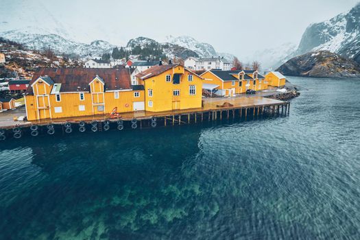 Panorama of Nusfjord authentic fishing village with yellow rorbu houses in Norwegian fjord in winter. Lofoten islands, Norway