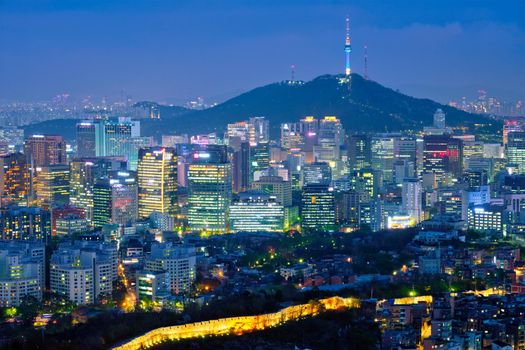 Seoul downtown cityscape illuminated with lights and Namsan Seoul Tower in the evening view from Inwang mountain. Seoul, South Korea.