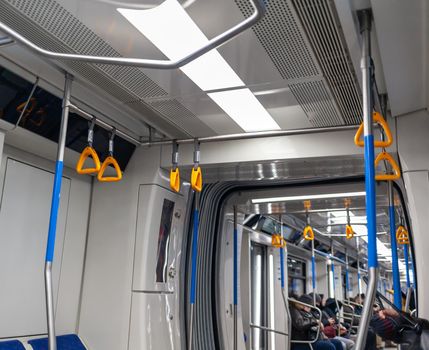 Public transport in the city. Moscow Metro. Yellow handrails for hands close-up. A full subway car lately in the evenings. There are a lot of people in a modern subway car.