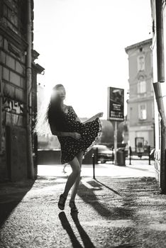 Portrait of stylish young woman. Brunette with curly hair in sundress posing on street.