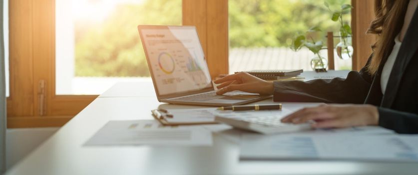 Business woman calculating domestic expenses involved in financial paperwork indoors, focused lady managing monthly banking payments summarizing utility bills and taxes at home.