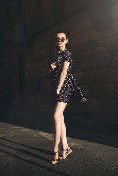 Portrait of stylish young woman. Brunette with curly hair in sundress posing on street.