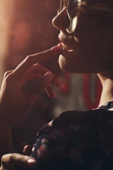 Close-up portrait of stylish young woman. Brunette in sundress posing on street. Finger near her lips