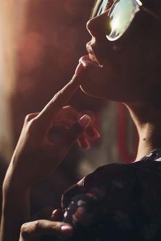 Close-up portrait of stylish young woman. Brunette in sundress posing on street. Finger near her lips