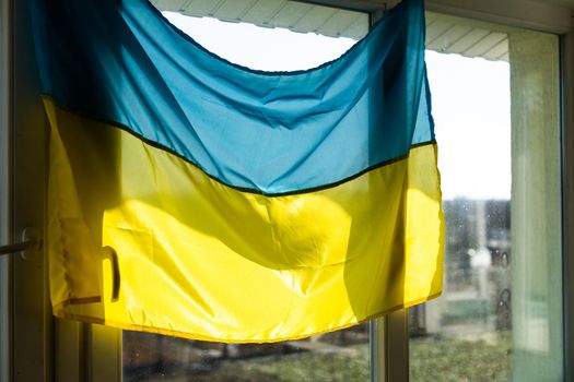 Support Ukraine. Ukrainian flag on the window. Place for text