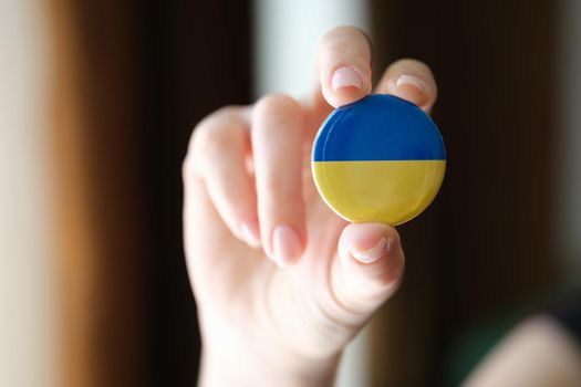 Ukraine flag badge in female hand. Help support and volunteering Ukraine and Ukrainians concept