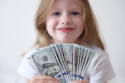 Portrait of smiling girl holding fan with dollars. Child benefits payment elements profitable family loan and capital concept