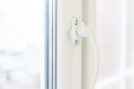 The handle of the new plastic door. White front door in a house under construction.