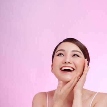 Beautiful elegant woman with bare shoulders clean skin spa treatments isolated on pink background