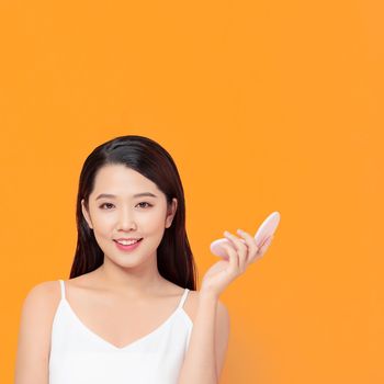 Smiling woman using lipstick on yellow background