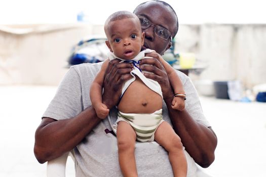 portrait of a man playing with his child whom he holds in his hands accompanied by a kiss