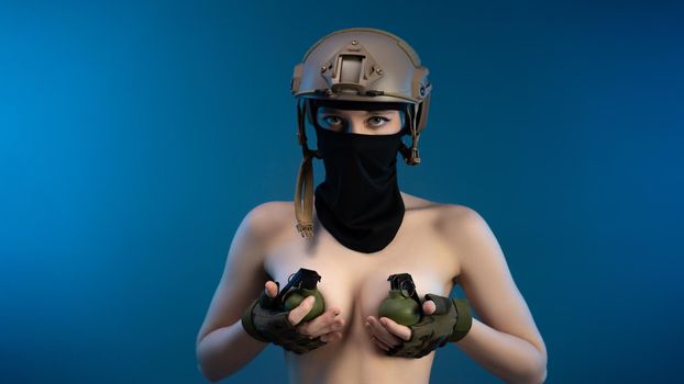 sexy girl soldier in a helmet, armed with an automatic rifle, in military clothes on a blue background