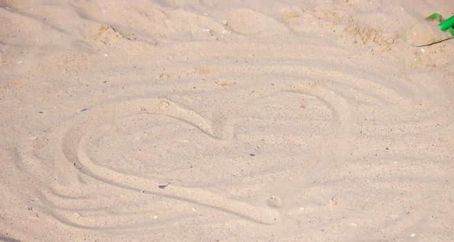 Heart drawn in the sand. Beach background. Top view. selective focus