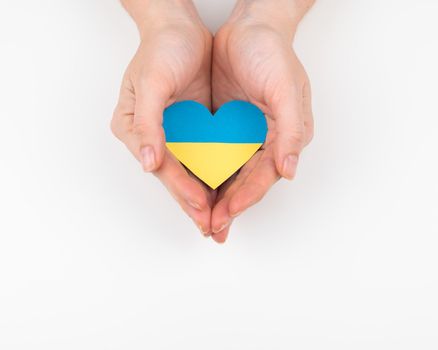 A woman holds a heart with the flag of Ukraine on a white background