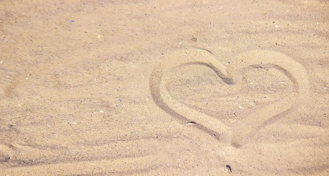 Heart drawn in the sand. Beach background. Top view. selective focus