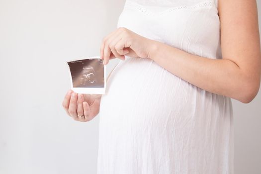 pregnant woman with a photo of ultrasound of pregnancy. enjoying pregnancy happy time. mother to be with cute big tummy.