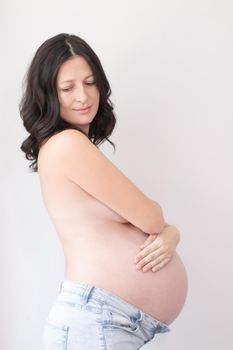 happy pretty woman enjoying pregnancy. mother to be is expecting parent. cute big tummy. pregnant brunette in light room.