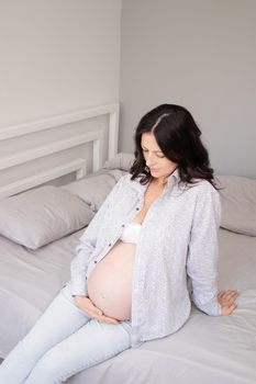 charming pregnant woman in shirt on bed. happy pregnancy.