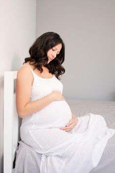 expecting mother with huge tummy. sweet pregnancy time. happy woman with pregnant belly in light bedroom. home cozy interior
