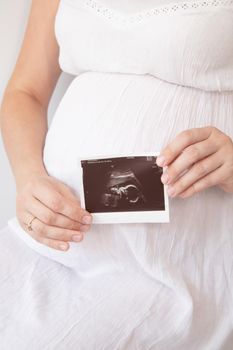 pregnant woman with a photo of ultrasound of pregnancy. enjoying pregnancy happy time. mother to be with cute big tummy.