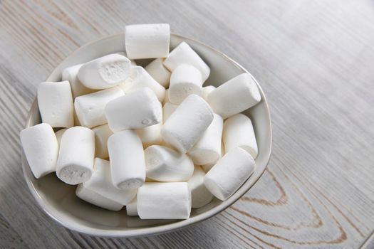 White marshmallows in a porcelain bowl on the table
