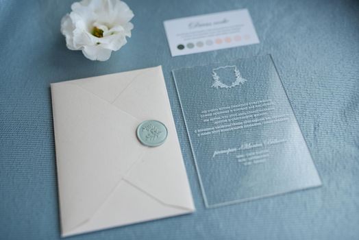 wedding invitation in a gray envelope on a table with green sprigs