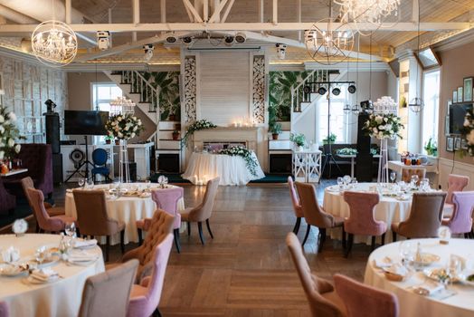 The presidium of the newlyweds in the banquet hall of the restaurant is decorated with candles and green plants, wisteria hangs from the ceiling