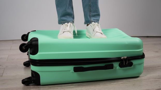 Woman standing with her feet on a suitcase