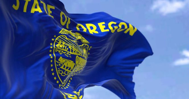 The US state flag of Oregon waving in the wind. Oregon is a state in the Pacific Northwest region of the Western United States. Democracy and independence.