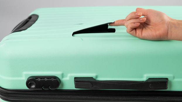 A woman demonstrates a broken suitcase on a white background. Damaged baggage during the flight