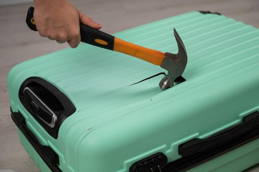 A woman hits a suitcase with a hammer on a white background