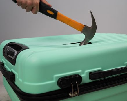 A woman hits a suitcase with a hammer on a white background